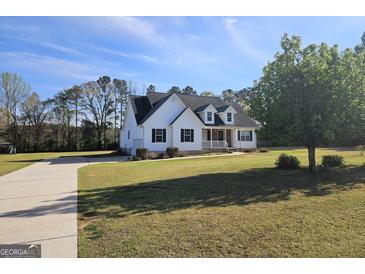 Charming white home with a welcoming front porch, green lawn, and a long driveway leading to the house at 1222 Snapping Shoals Rd, Mcdonough, GA 30252