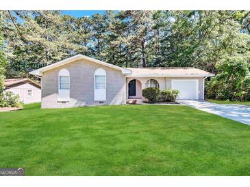 Charming one-story home featuring a brick exterior, well-maintained lawn, and mature trees at 6635 Hidden Brook Trl, South Fulton, GA 30349