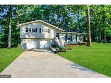 Split-level home boasts well-maintained lawn and a two car garage, nestled among mature trees at 120 Gran De, Atlanta, GA 30349