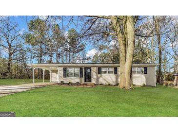 Charming single-story home with a well-maintained lawn and mature trees at 5960 John St, Austell, GA 30106