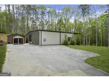 Modern home exterior featuring a large concrete driveway and additional gazebo structure at 803 Bentley Hill Rd, Stockbridge, GA 30281