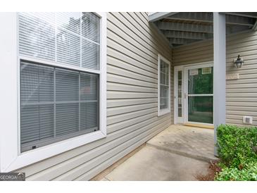 Exterior shot of the townhome front entrance featuring beige siding, and a storm door at 702 Las Brasis Ct, Peachtree City, GA 30269