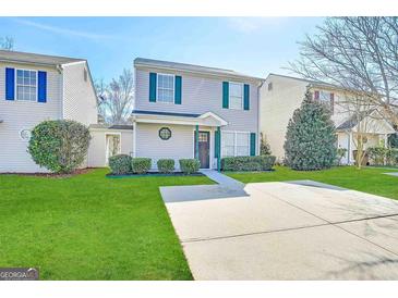Charming two-story home with a well-maintained lawn and concrete driveway on a sunny day at 371 Coral Cir, Mcdonough, GA 30253