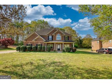 Charming two-story brick home with a well-manicured lawn and lush green landscaping at 117 Berkeley Way, Hampton, GA 30228