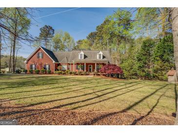 Charming brick home featuring a spacious front yard with mature trees and a welcoming covered porch at 1744 Elks Club Rd, Covington, GA 30014
