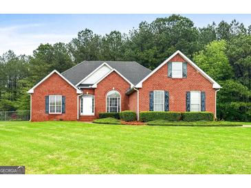 Charming brick home with a well-manicured lawn and mature trees in the background, showcasing classic suburban living at 205 Wynnfield Way, Mcdonough, GA 30252
