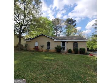 Charming one-story home with brick exterior, arched windows and a green lawn at 2884 Haddon Dr, Rex, GA 30273
