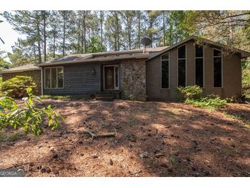Charming home with a combination of stone and wood siding and a lush natural front yard landscape at 204 Mitchell Rd, Fayetteville, GA 30214