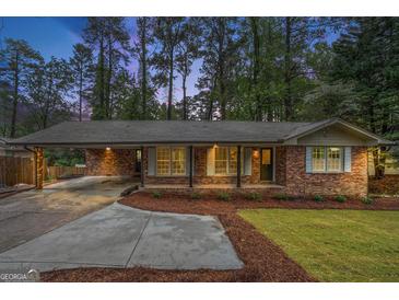 Charming brick home featuring a welcoming front porch, light blue shutters and a covered carport at 2695 Peeler Rd, Doraville, GA 30360