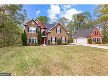 Beautiful two-story home with stone facade, red accents, and a well-manicured lawn at 368 Yellowwood Dr, Sharpsburg, GA 30277