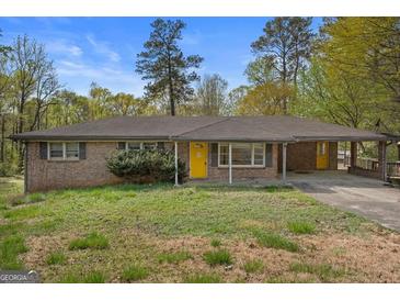 Charming brick ranch-style home with a yellow door, covered porch, and well-maintained landscaping at 6064 Oak Hill Dr, Austell, GA 30168