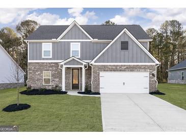 Charming two-story home features a brick and gray facade, well-manicured lawn, and a two-car garage at 3402 Arabian Farm Ln, Dacula, GA 30019