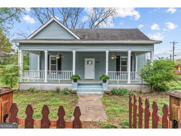 Charming home with a welcoming front porch, columns, and a quaint fenced yard at 1202 Emory St, Oxford, GA 30054