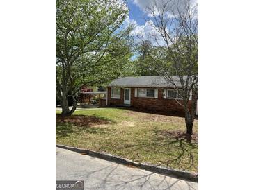 Charming brick home featuring a covered carport and a well-maintained front yard with mature trees at 1079 Pine Ne St, Conyers, GA 30012