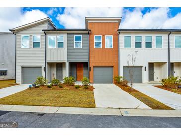 Charming townhome featuring a well-manicured lawn and a gray garage door, inviting and stylish curb appeal at 1516 Parks Edge Nw Ln, Atlanta, GA 30318