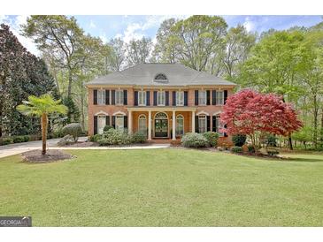 Charming two-story brick home with manicured lawn, mature trees, and classic black shutters at 285 Broadmoor Dr, Fayetteville, GA 30215