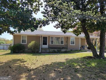 Charming one-story home with tan siding, mature trees, and a welcoming front porch at 4365 Newton Cir, Douglasville, GA 30134