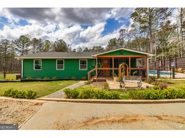 Charming green home featuring a covered porch, landscaped garden, and quaint walkway at 168 Lakeview Dr, Grantville, GA 30220