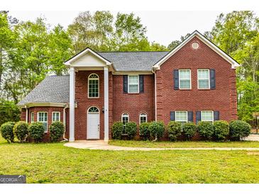 Traditional two-story brick home featuring black shutters, a gabled roof, and a well-manicured lawn at 1015 Middlebrook Dr, Mcdonough, GA 30252