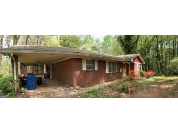 Charming brick home with a covered carport and mature landscaping in a tranquil setting at 8395 Rivertown Rd, Fairburn, GA 30213