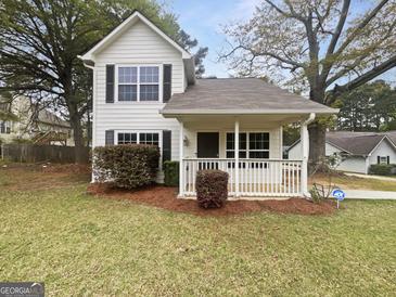 Charming two-story home featuring a covered porch and manicured front yard at 7747 Roundtree Xing, Riverdale, GA 30274