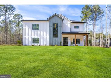 Modern farmhouse with white siding, a gray accent, black windows, and a lush green lawn on a sunny day at 140 Wesley Pl, Fayetteville, GA 30214
