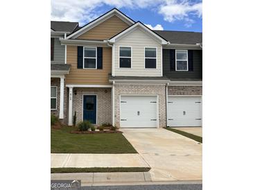 Townhome features brick accents, a two-car garage, and a blue front door at 8708 Lakeview Commons # 47, Jonesboro, GA 30238
