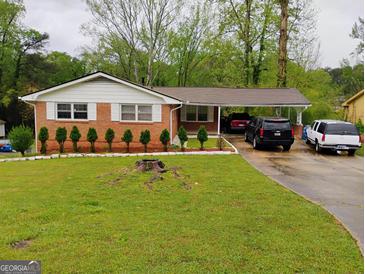 Charming brick home with a well-manicured lawn and covered parking at 6501 River Run Rd, Riverdale, GA 30274