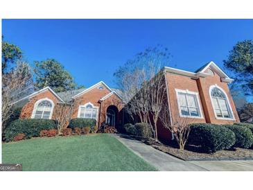 Stately brick home featuring a manicured front lawn, mature landscaping and arched windows at 1090 Crown River Pkwy, Mcdonough, GA 30252