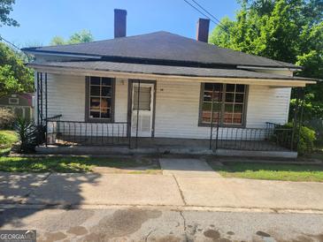 Quaint single-story home featuring a covered front porch, a simple yard, and a vintage charm at 34 Pine St, Porterdale, GA 30014