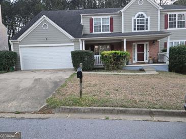 Charming two-story home with a two-car garage, front porch, and manicured lawn at 888 Shadow Lakes Dr, Lithonia, GA 30058