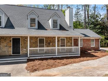 Charming home with a stone facade, dormer windows, and a welcoming front porch at 9055 Carroll Manor Dr, Sandy Springs, GA 30350