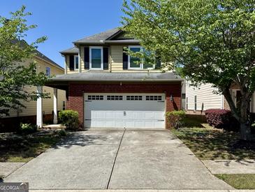 Charming two-story home features a red brick facade with a two-car garage and a well-manicured lawn at 2517 Oakleaf Rdg, Lithonia, GA 30058