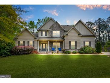 Charming two-story home featuring a manicured lawn, stone accents, and a welcoming front porch with blue rocking chairs at 229 Primstone Way, Mcdonough, GA 30253