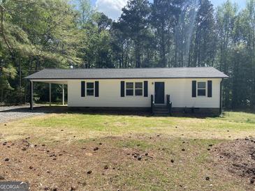 Charming single-story home features white siding, black shutters, and a covered carport for convenient parking at 300 Wood Rd., Hampton, GA 30228
