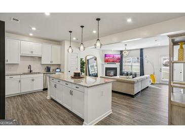 Open-concept living room showcases a modern kitchen with island and a cozy fireplace at 375 Crider Ct, Woodstock, GA 30188