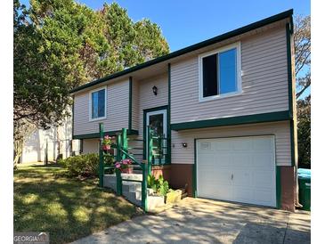 Charming two-story home featuring vinyl siding, green trim, a garage, and landscaped front yard at 2406 Redfield Dr, Norcross, GA 30071