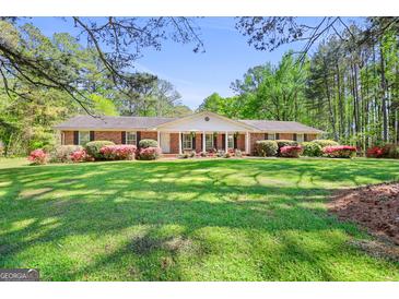 Charming brick ranch home featuring a lush, green lawn and mature landscaping at 242 Hickory Rd, Fayetteville, GA 30214