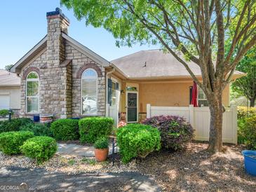 Charming home exterior featuring a stone facade, chimney, manicured landscaping, and a welcoming entrance at 307 Gladstone Dr, Mcdonough, GA 30253