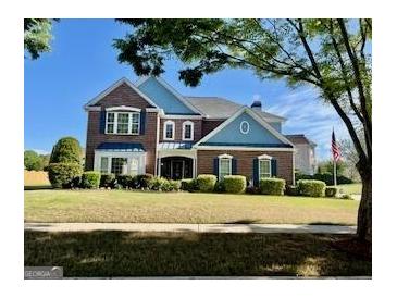 Charming two-story brick home with a manicured lawn and patriotic flag display at 1600 Prospect Pl, Locust Grove, GA 30248