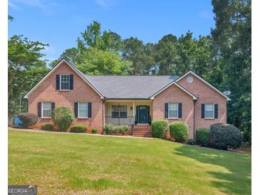 Charming brick home featuring a well-manicured lawn and mature trees on a sunny day at 75 The Farm Rd, Mcdonough, GA 30252