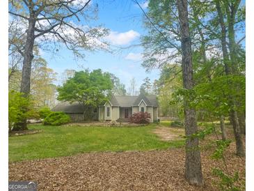 Charming single-story home with manicured lawn, lush trees, and stone accents, perfect for a serene living experience at 100 Little Creek Dr, Sharpsburg, GA 30277