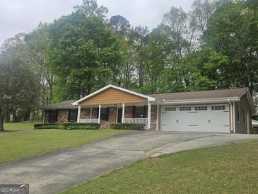 Charming brick home with a welcoming front porch, well-manicured lawn, and an attached two-car garage at 103 Belair Ln, Stockbridge, GA 30281