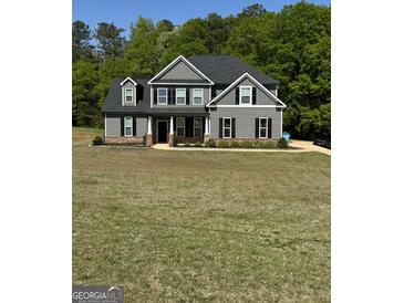 Charming two-story home with gray siding, black shutters, and a well-manicured lawn surrounded by lush green trees at 935 S Laney Rd, Locust Grove, GA 30248