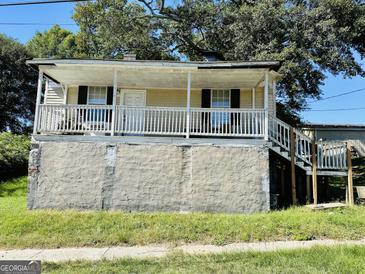 Inviting exterior of a home featuring a covered porch, a stone foundation, and a well-maintained lawn at 7 Ivy St, Porterdale, GA 30014