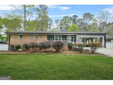 Charming brick home featuring a well-manicured lawn and an inviting covered carport at 3387 Oak Dr, Lawrenceville, GA 30044