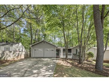 Charming single-story home featuring a spacious two-car garage and inviting front porch surrounded by lush greenery at 385 Lakeshore Dr, Stockbridge, GA 30281
