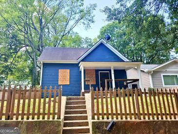 Charming blue home with inviting front porch and wooden fence, full of potential at 674 Jett Nw St, Atlanta, GA 30318