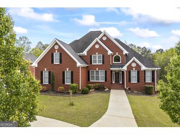 Impressive red brick home featuring manicured lawn, black shutters, and elegant architectural detailing at 2351 Rabbit Farm Cir, Loganville, GA 30052