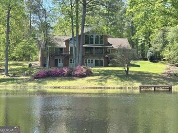 Beautiful exterior view of the brick home overlooking a scenic lake and lush greenery at 4383 Pool Rd, Winston, GA 30187